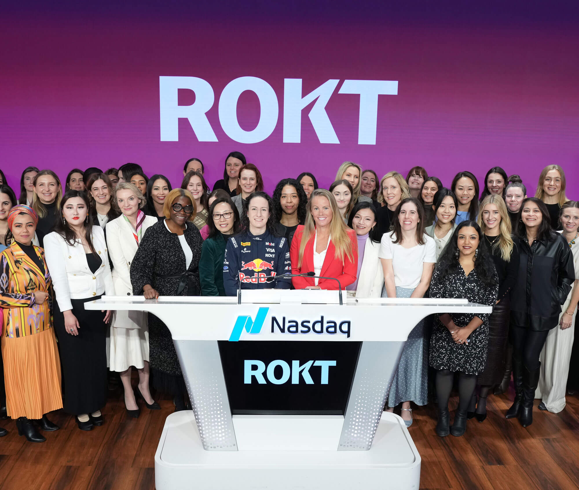 Group of diverse women standing behind a Nasdaq podium with ROKT branding on screen and backdrop.
