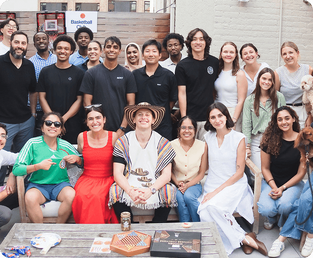 Diverse group of people smiling and posing together in an outdoor setting with games on a table.