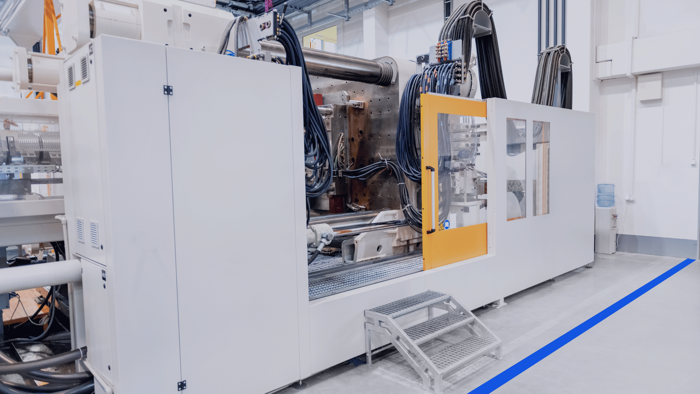 Industrial plastic injection molding machine on a clean factory floor for real-time OEE monitoring.