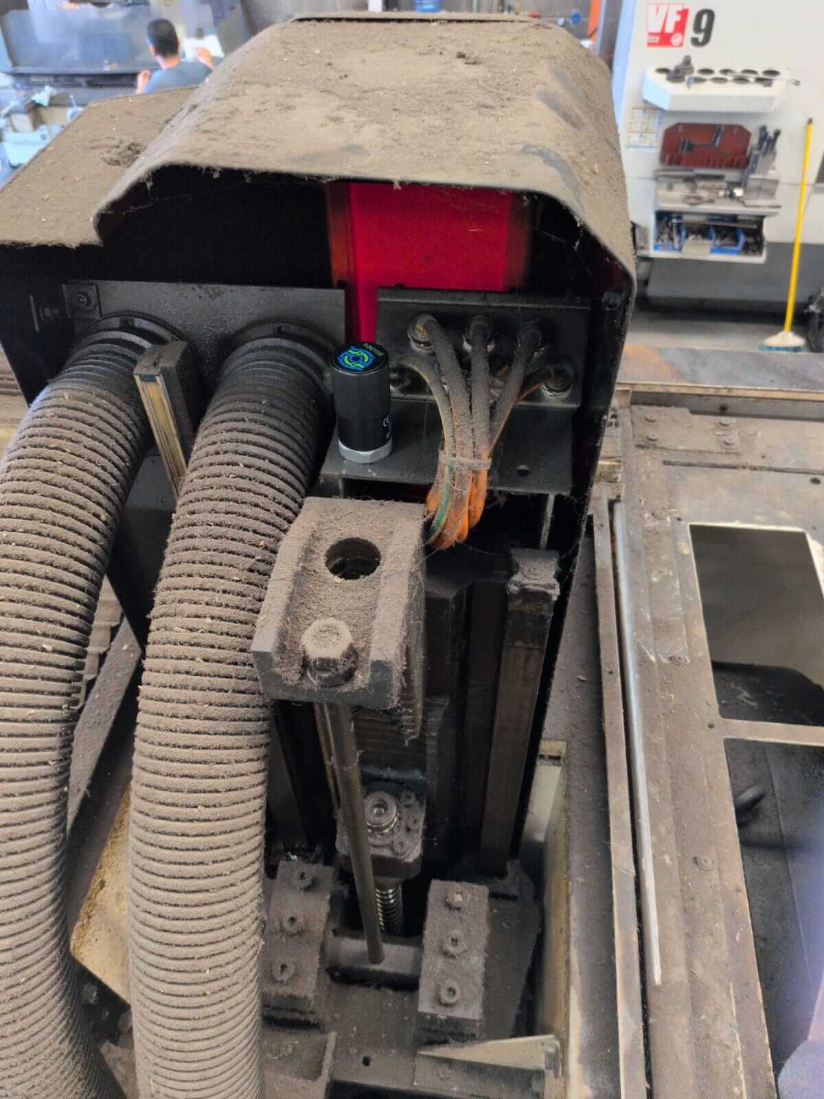 Sensor de monitoreo de máquinas SensFlo instalado dentro de un equipo CNC junto a mangueras, cableado y componentes mecánicos.