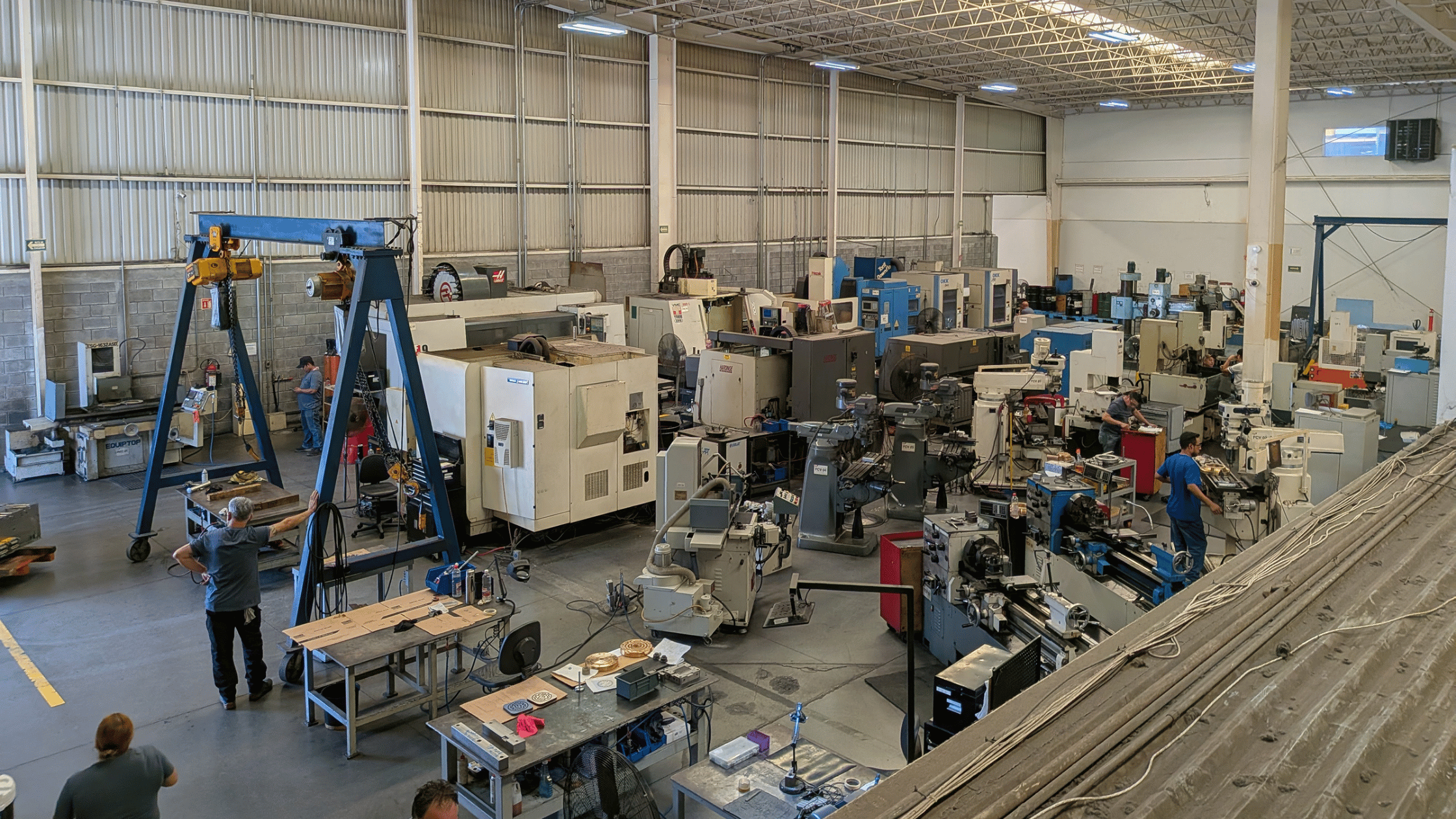 Machine shop floor with legacy CNC mills, lathes, machining equipment, and operators in production.