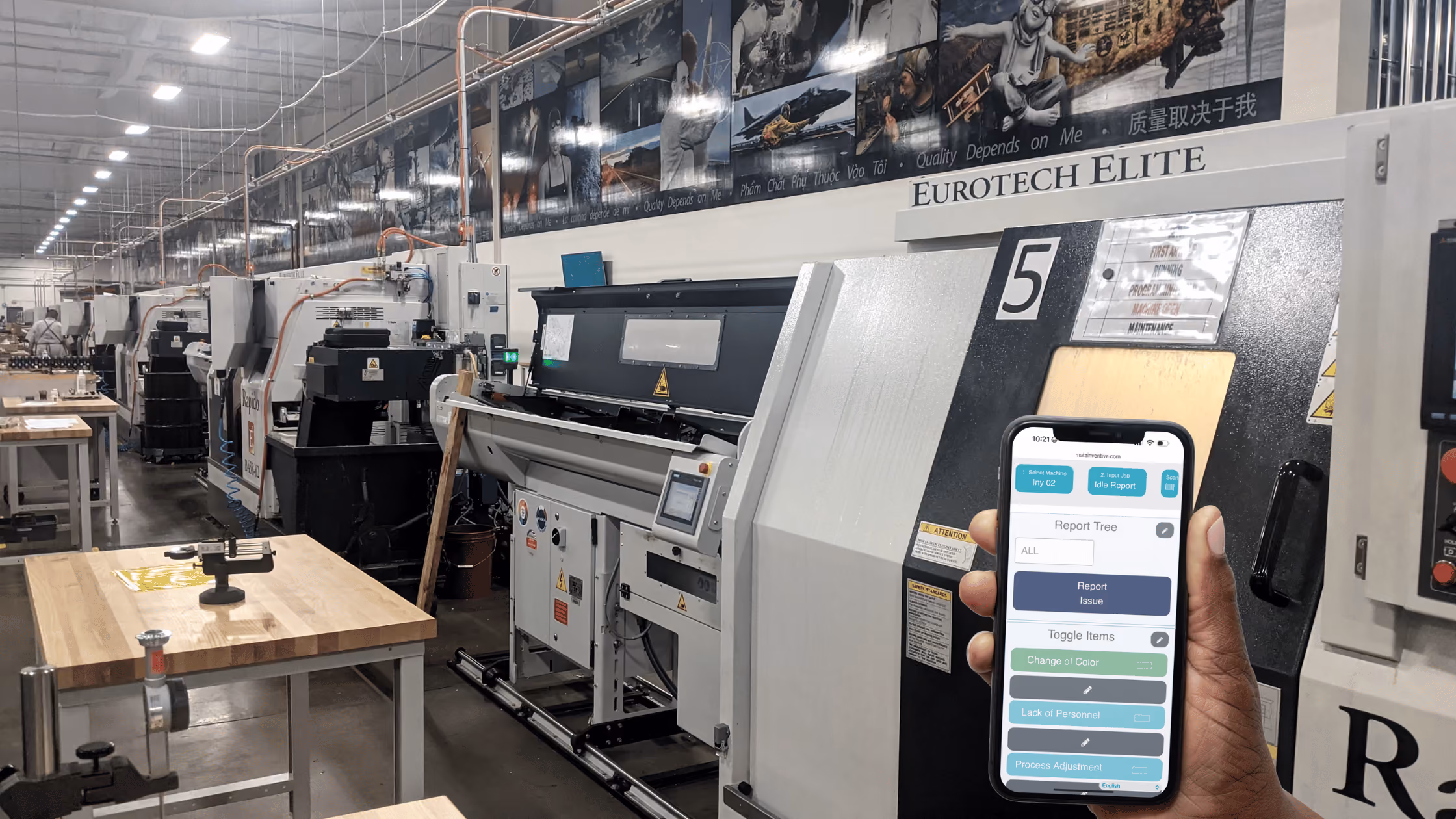 Operator using a mobile app to report machine issues and downtime reasons beside CNC equipment in a manufacturing facility for OEE monitoring.