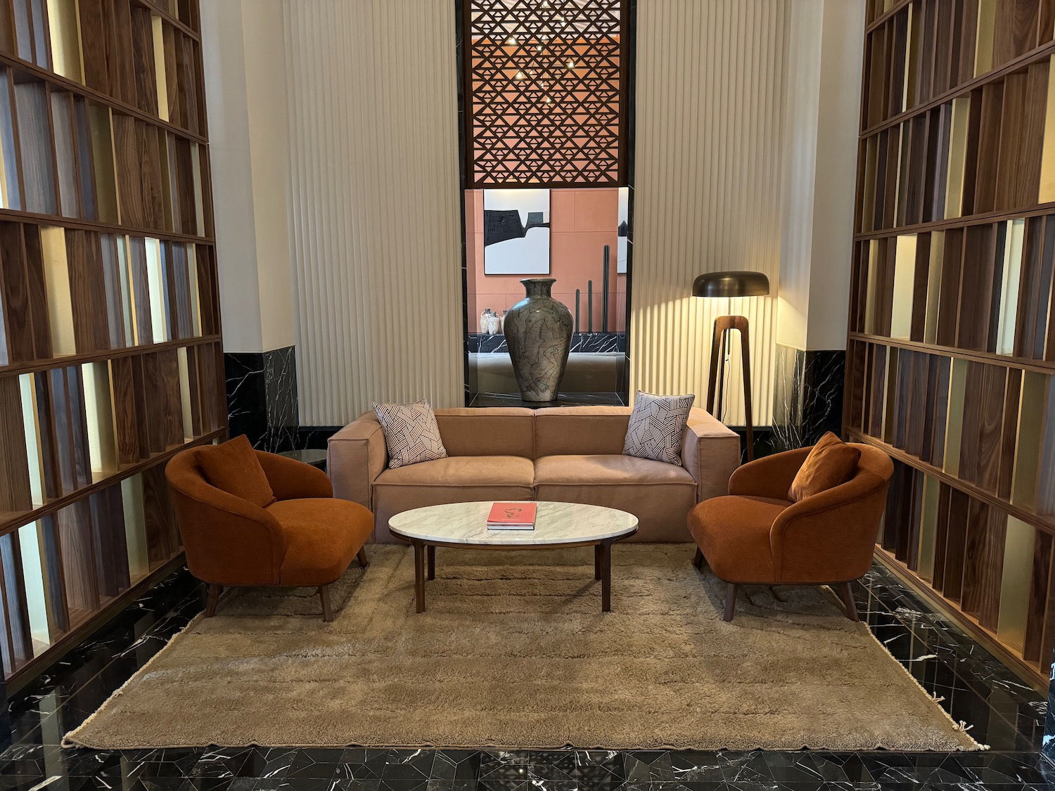 Modern interior design setup with sofa, armchairs, marble coffee table, floor lamp, and decorative elements in a stylish living room.