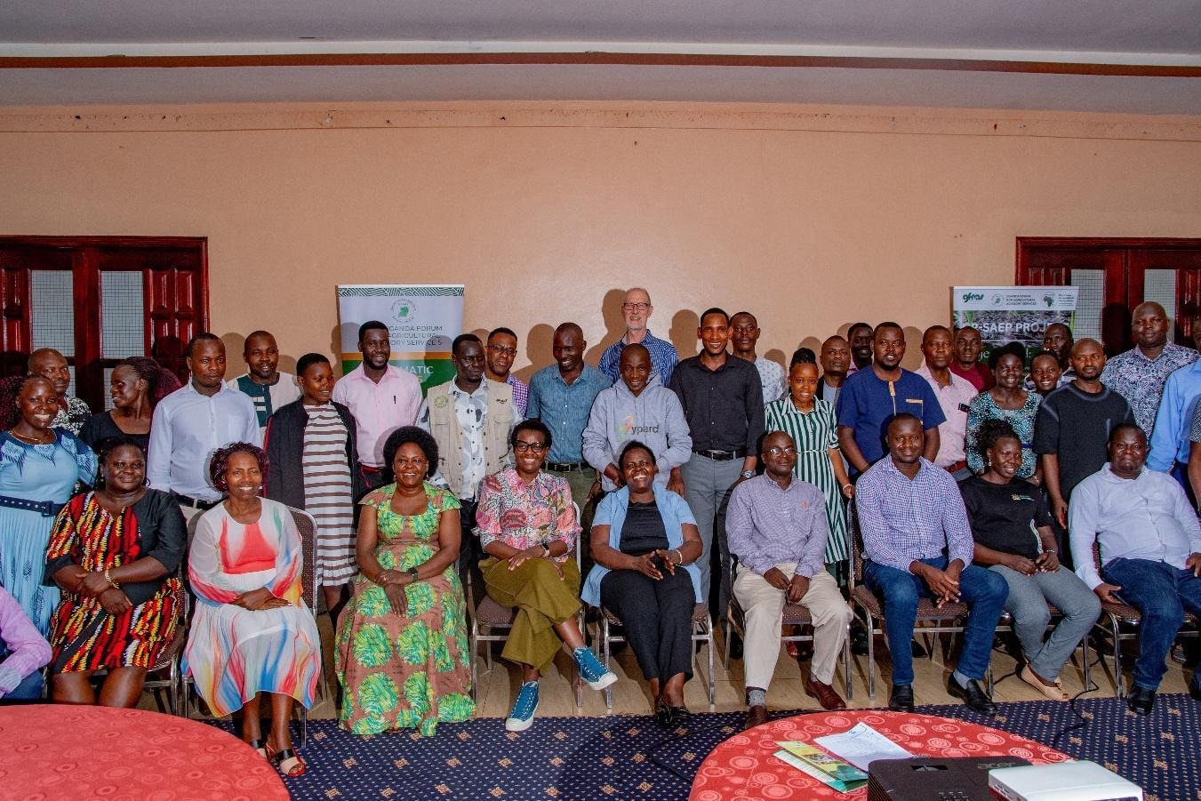 The image depicts a group of people gathered in a room, likely attending an event or meeting, with some wearing patterned clothing and others in plain attire.AI-generated content may be incorrect.