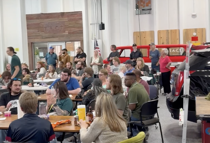 A teacher guiding his student on a wood cutting machine