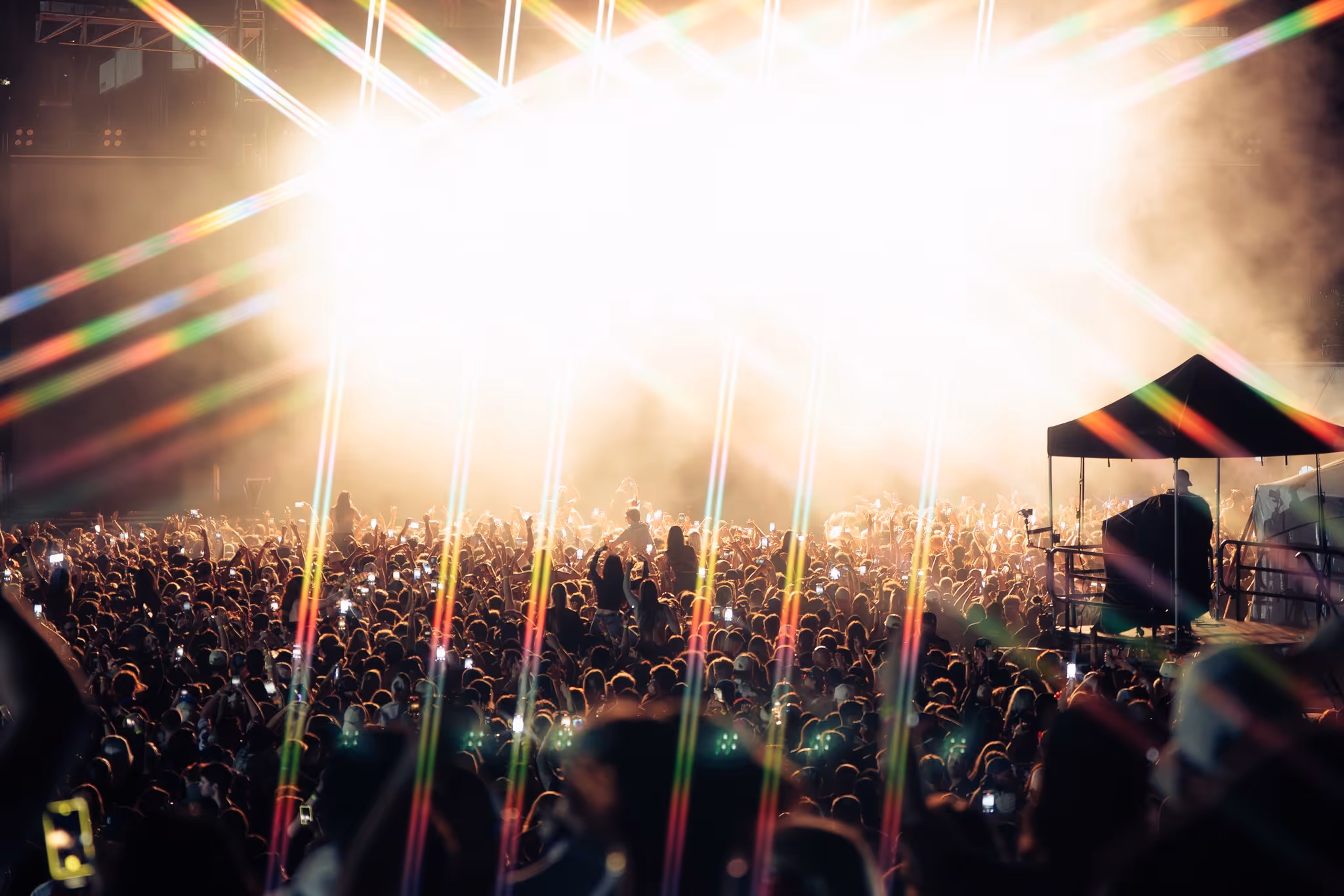 Festival crowd with phones raised in a starburst of white stage light at night, Magnetic World Music Festival, Halifax
