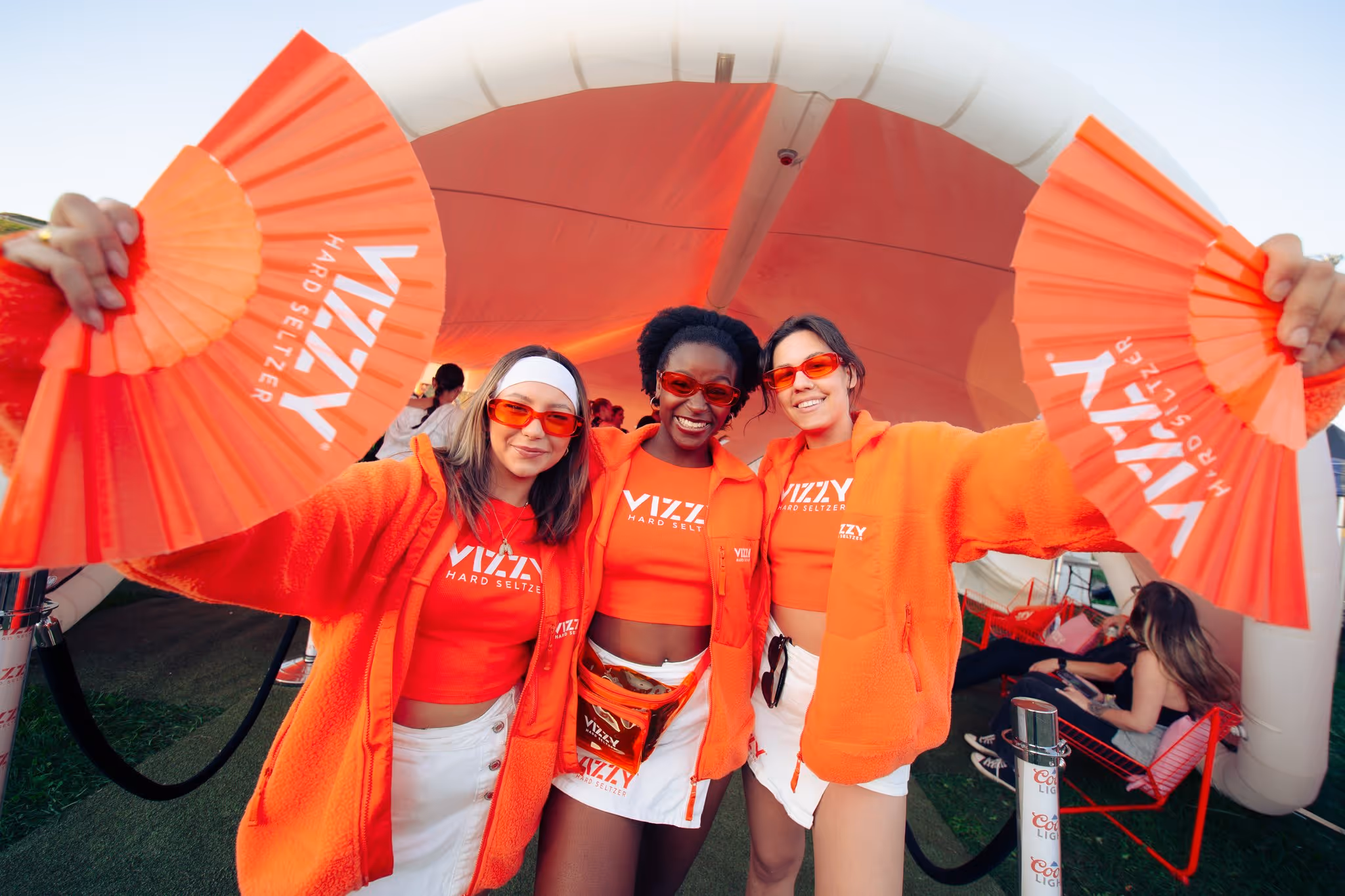 Vizzy brand ambassadors with orange fans at a sponsor activation on Citadel Hill, Magnetic World Music Festival, Halifax