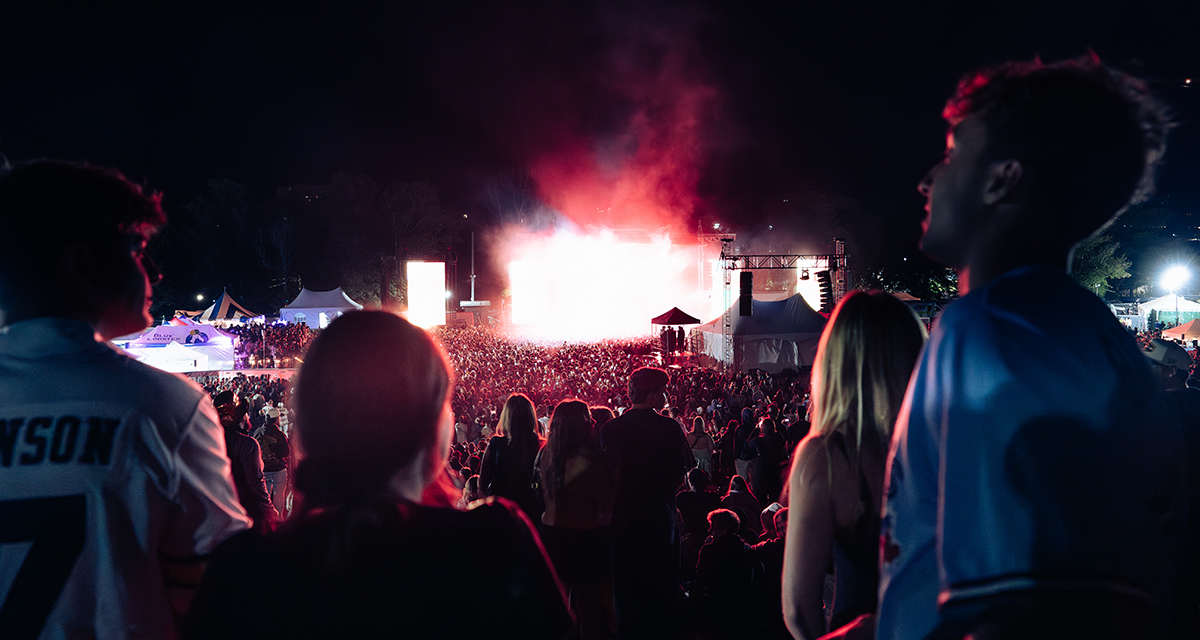 Festival crowd with phones raised in a starburst of white stage light at night, Magnetic World Music Festival, Halifax