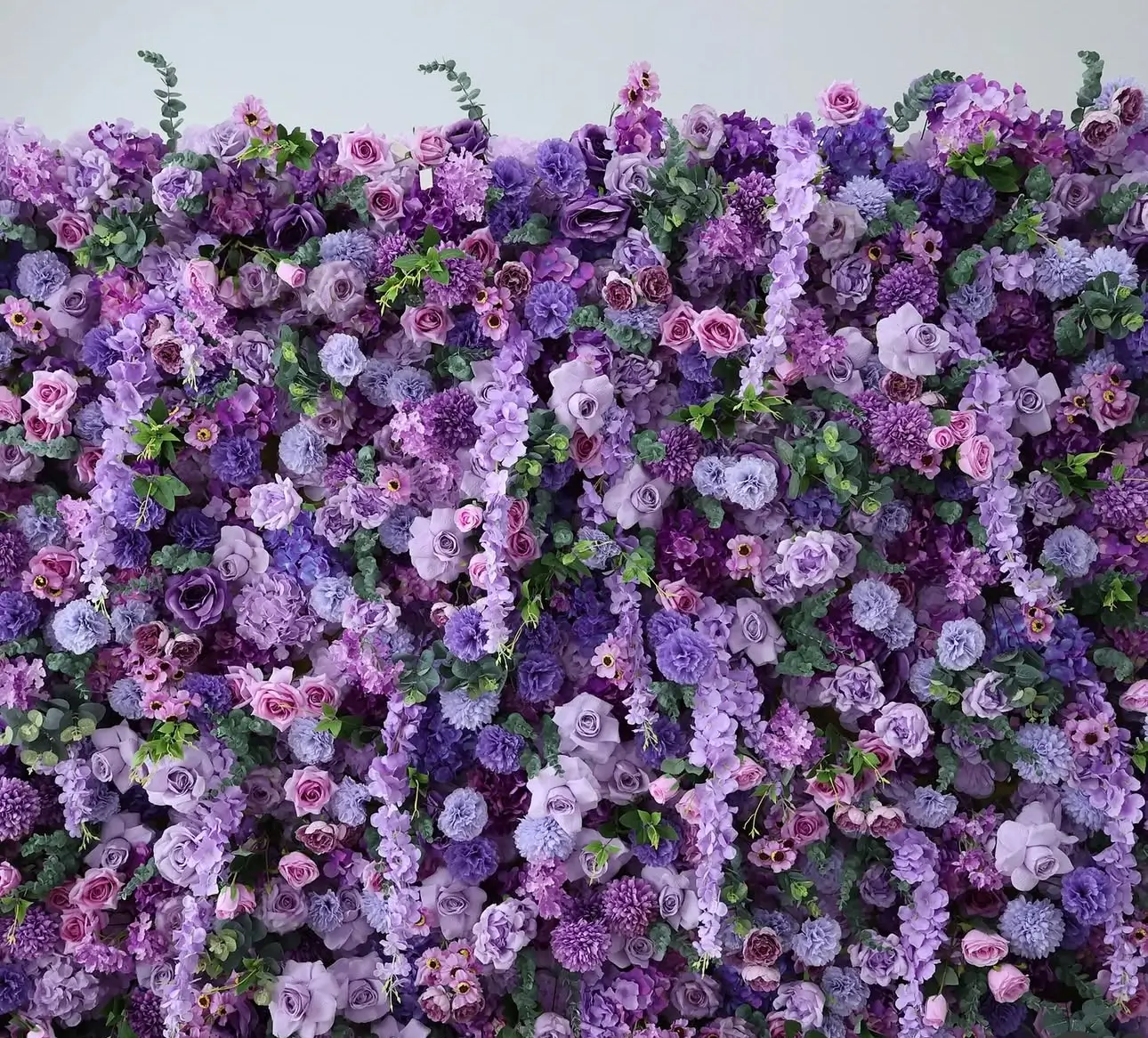 A wall adorned with a lush arrangement of purple and pink flowers, forming a striking floral backdrop.