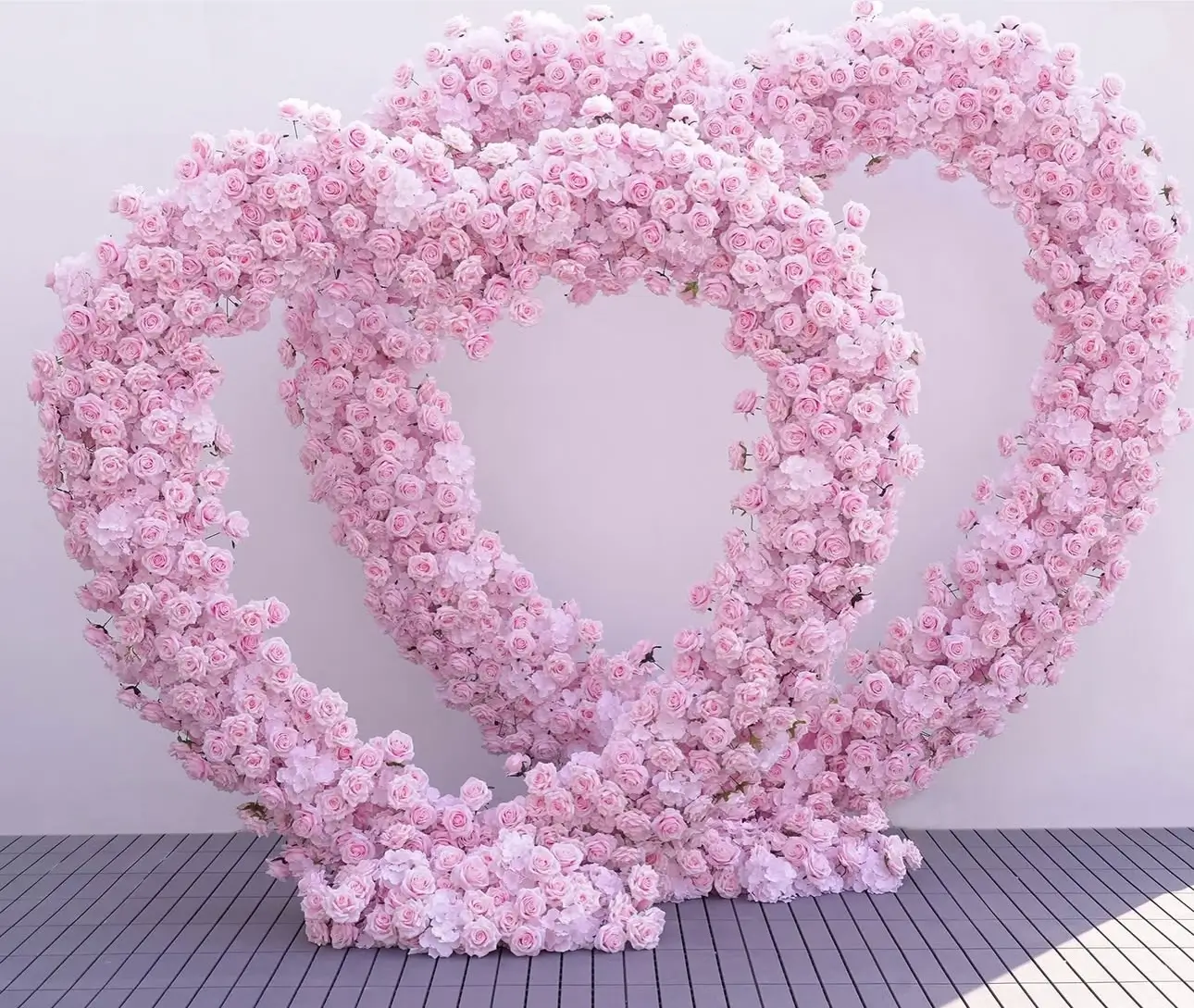 A large heart-shaped arrangement of pink roses on a white background, symbolizing love and celebration.