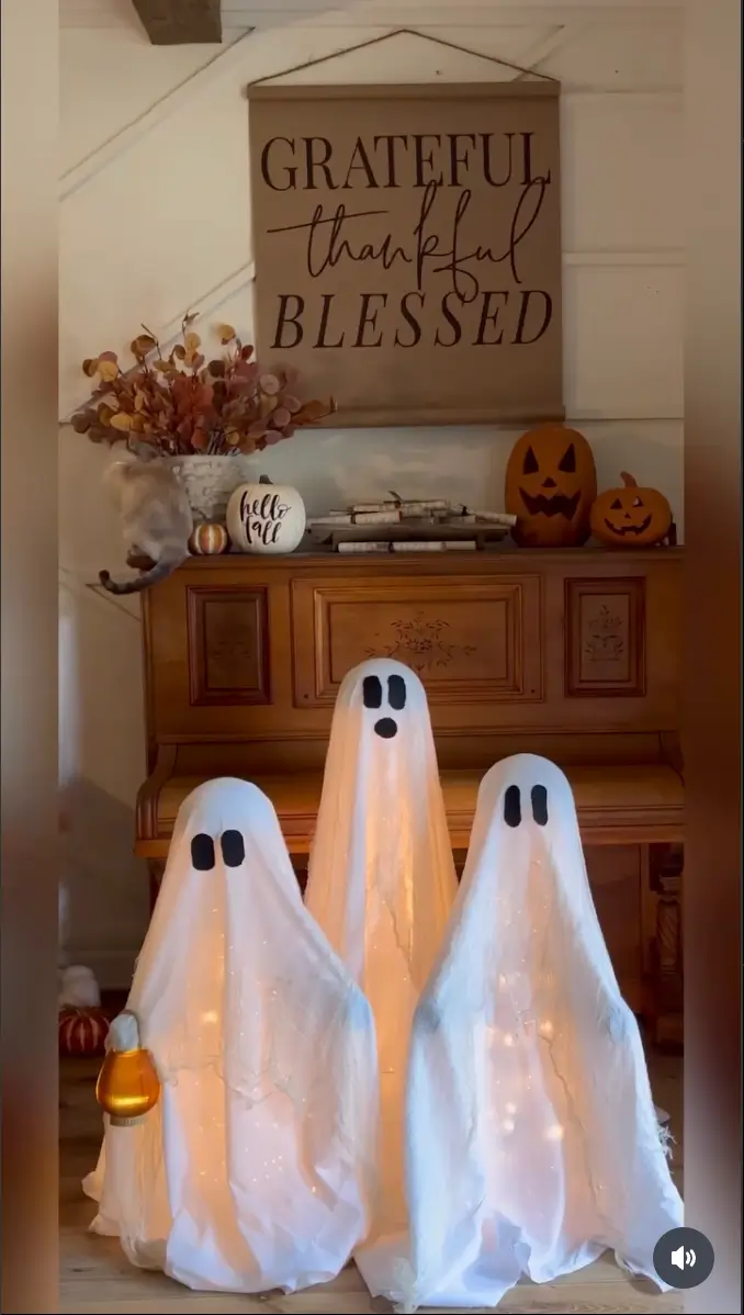 Three fake ghosts sit on a table beside a sign that reads "Grateful and Blessed," showcasing a DIY Halloween decoration.