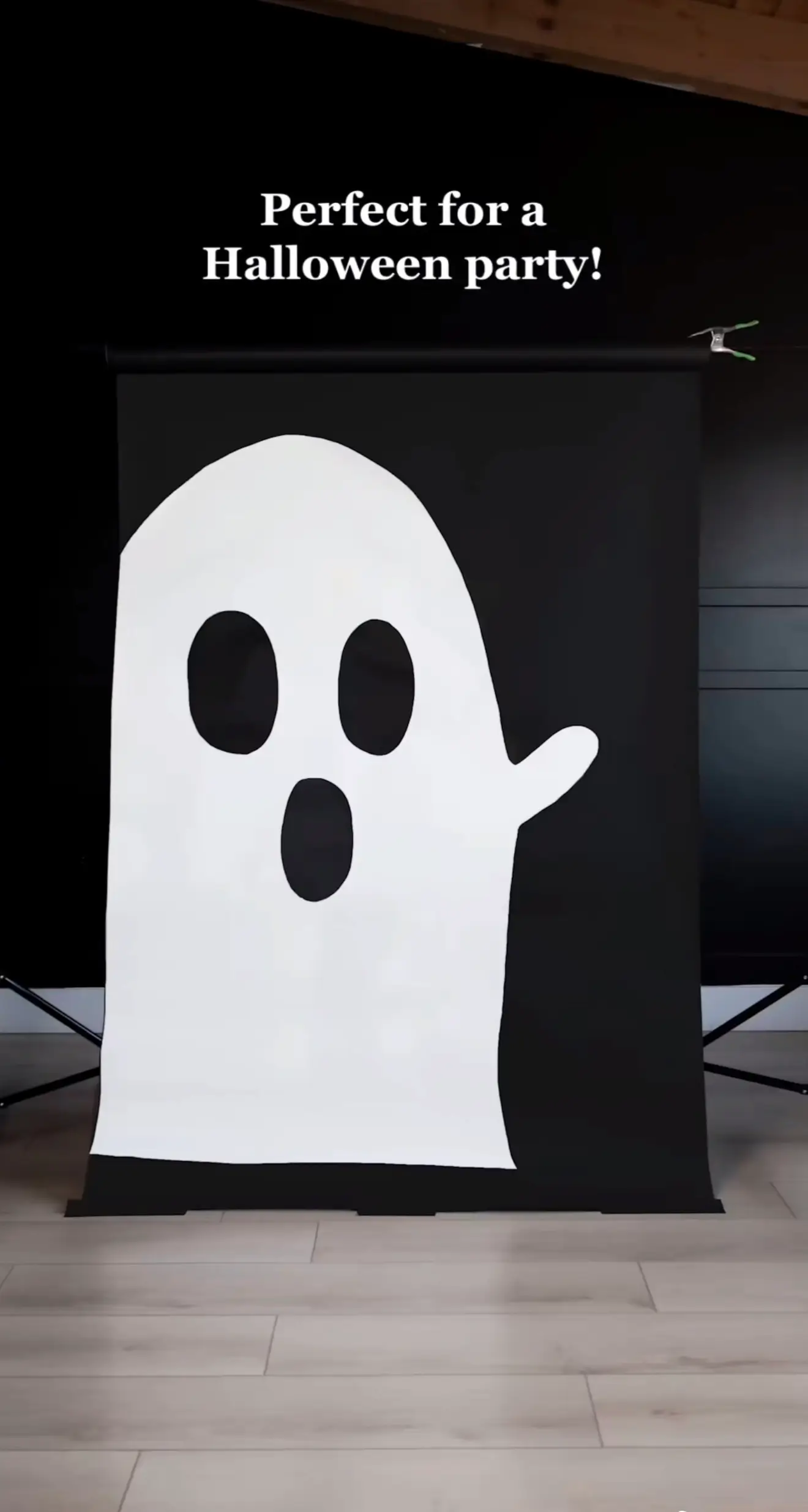 DIY Halloween backdrop featuring a ghost with a white face against a black background.