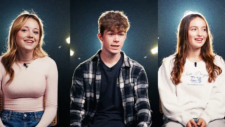 Three teenagers sitting and smiling against a dark background with subtle lights.