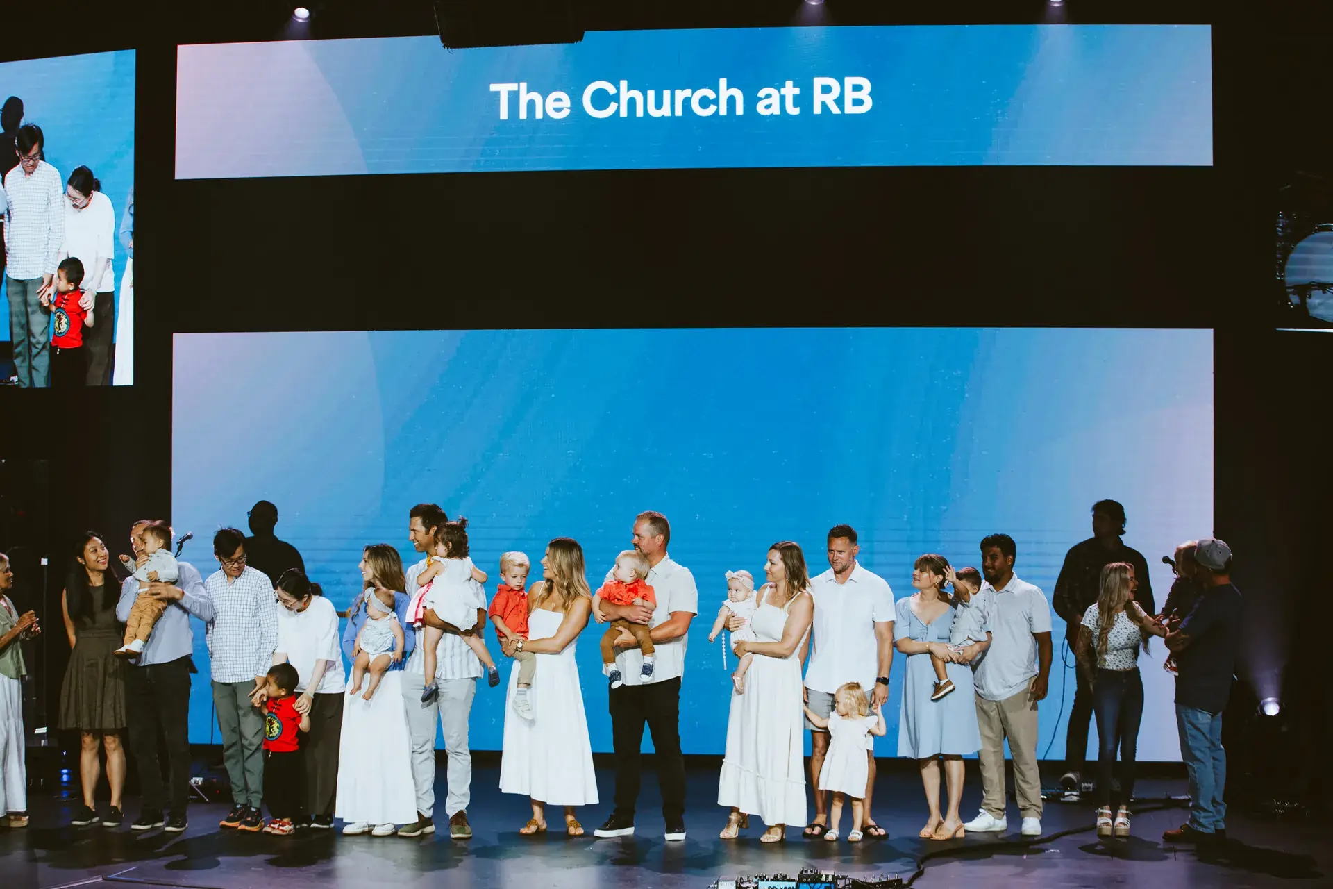 Group of families with young children on stage for a child dedication ceremony at The Church at RB.