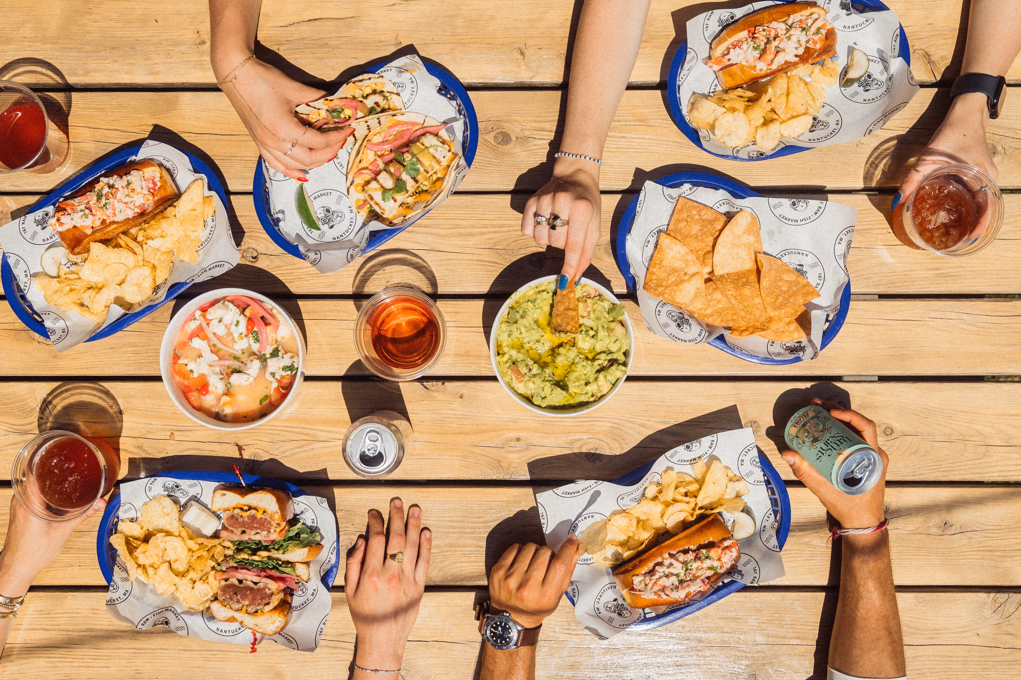 A close-up of friends enjoying a meal and drinks at 167 Raw Nantucket.