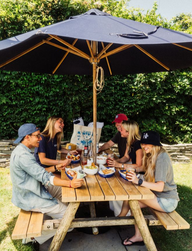 Group of friends enjoying seafood together under an umbrella at 167 Raw Nantucket