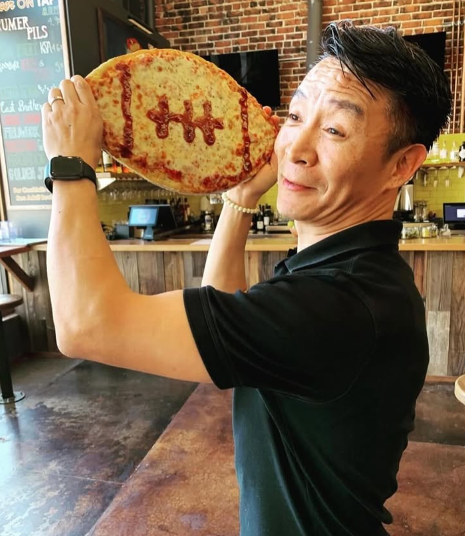 Man holding football shaped pizza