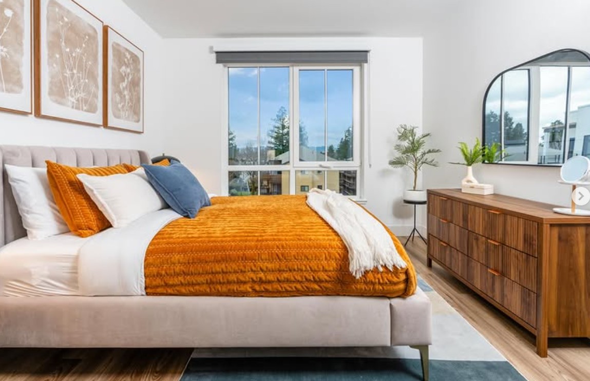 bedroom with windows, a dresser, and a bed with an orange blanket