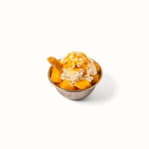 Bingsu coréen à la mangue servi au restaurant Chikin Bang, dessert glacé avec crème fouettée, morceaux de mangue fraîche et coulis.