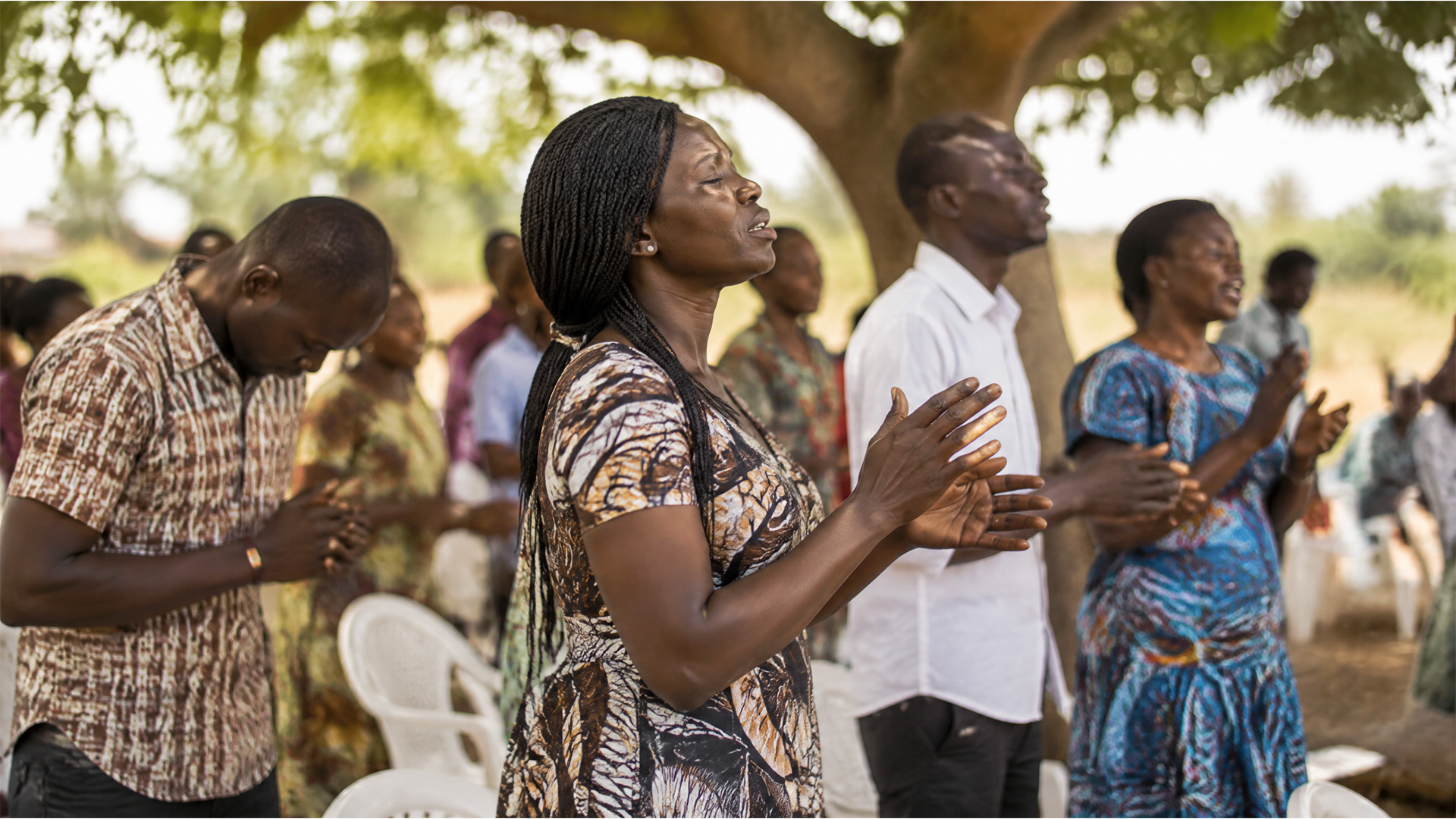 Togolese believers worshiping outdoors under a tree