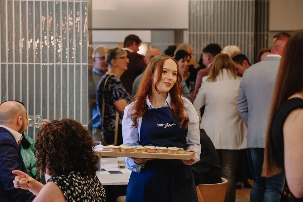 A female server at The Goat with a board of appetisers at a party