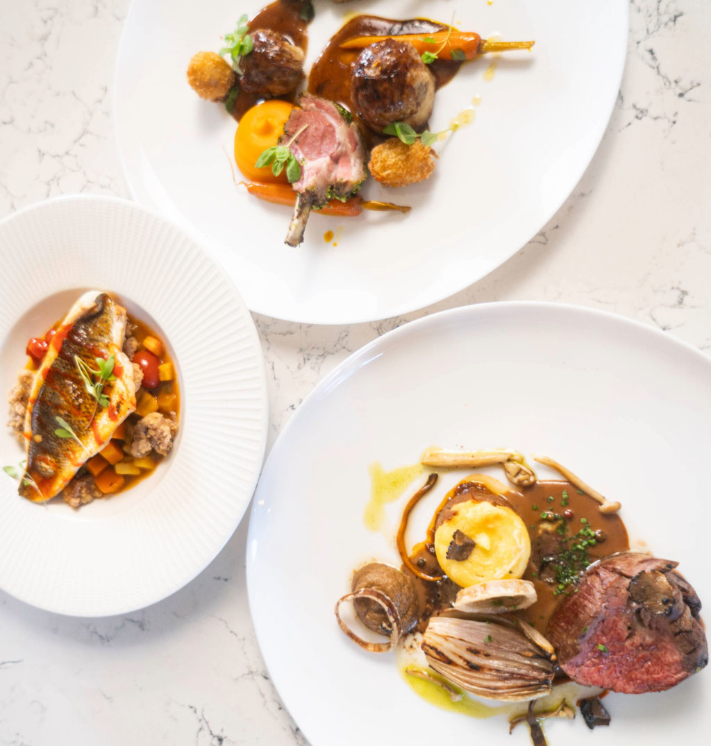 A male chef plating up food in a kitchen