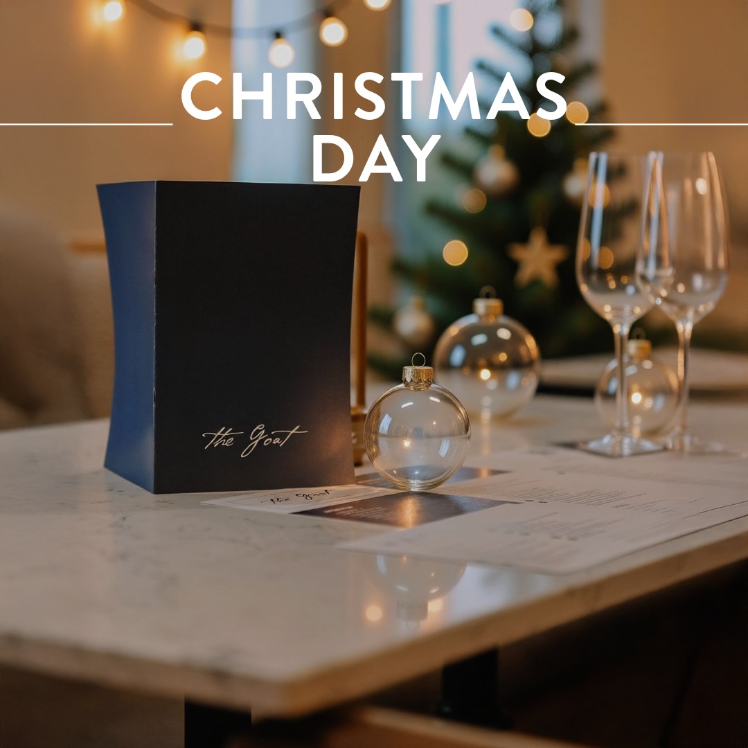 The Goat menu with glass bauble and wine glasses on festive table.