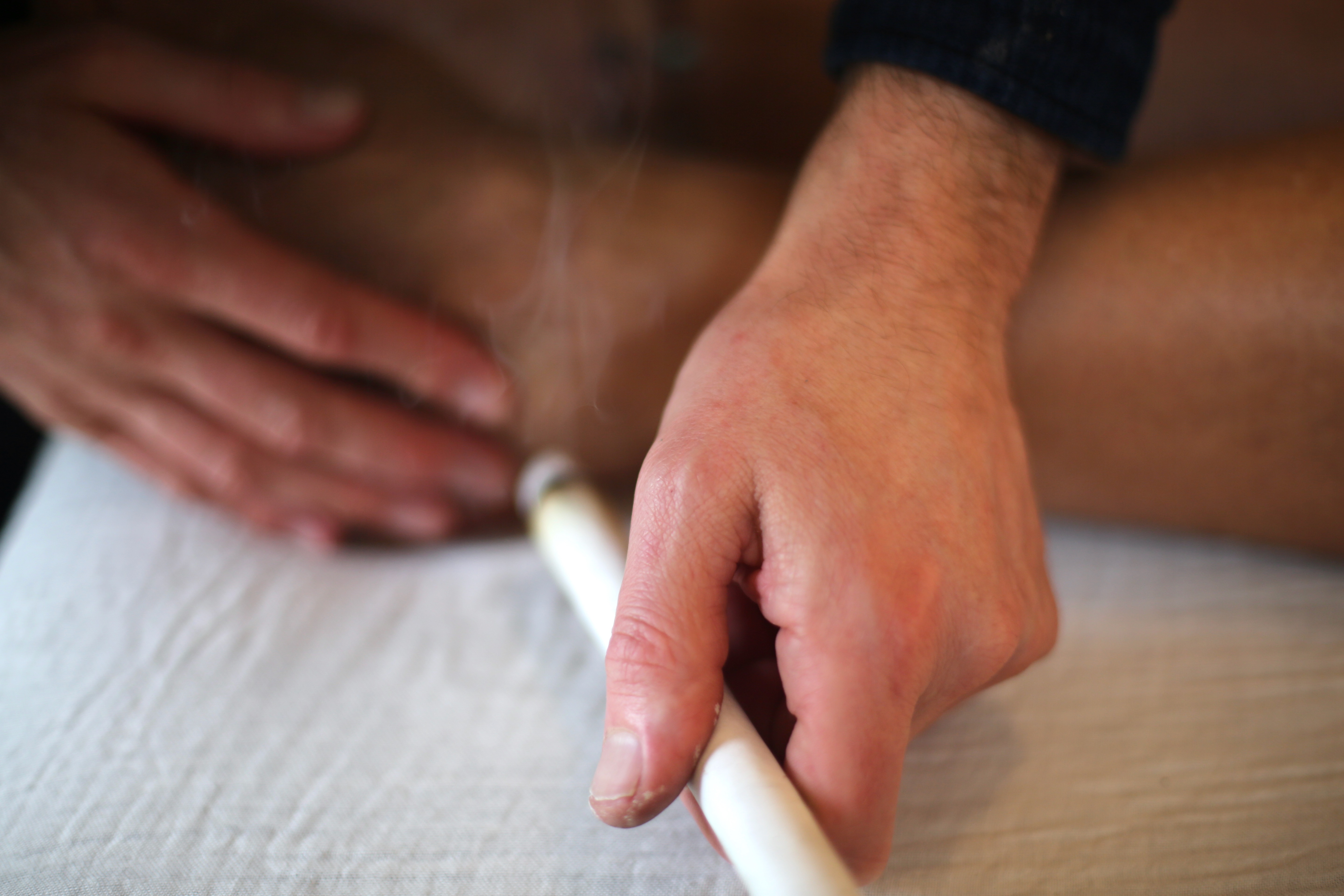 Person marking another person's hand with a pen, focusing on hands against a blurred background.