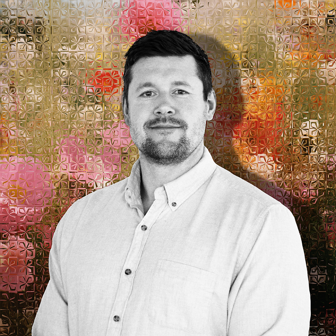 Professional headshot of a man in black and white on a multi-colored background