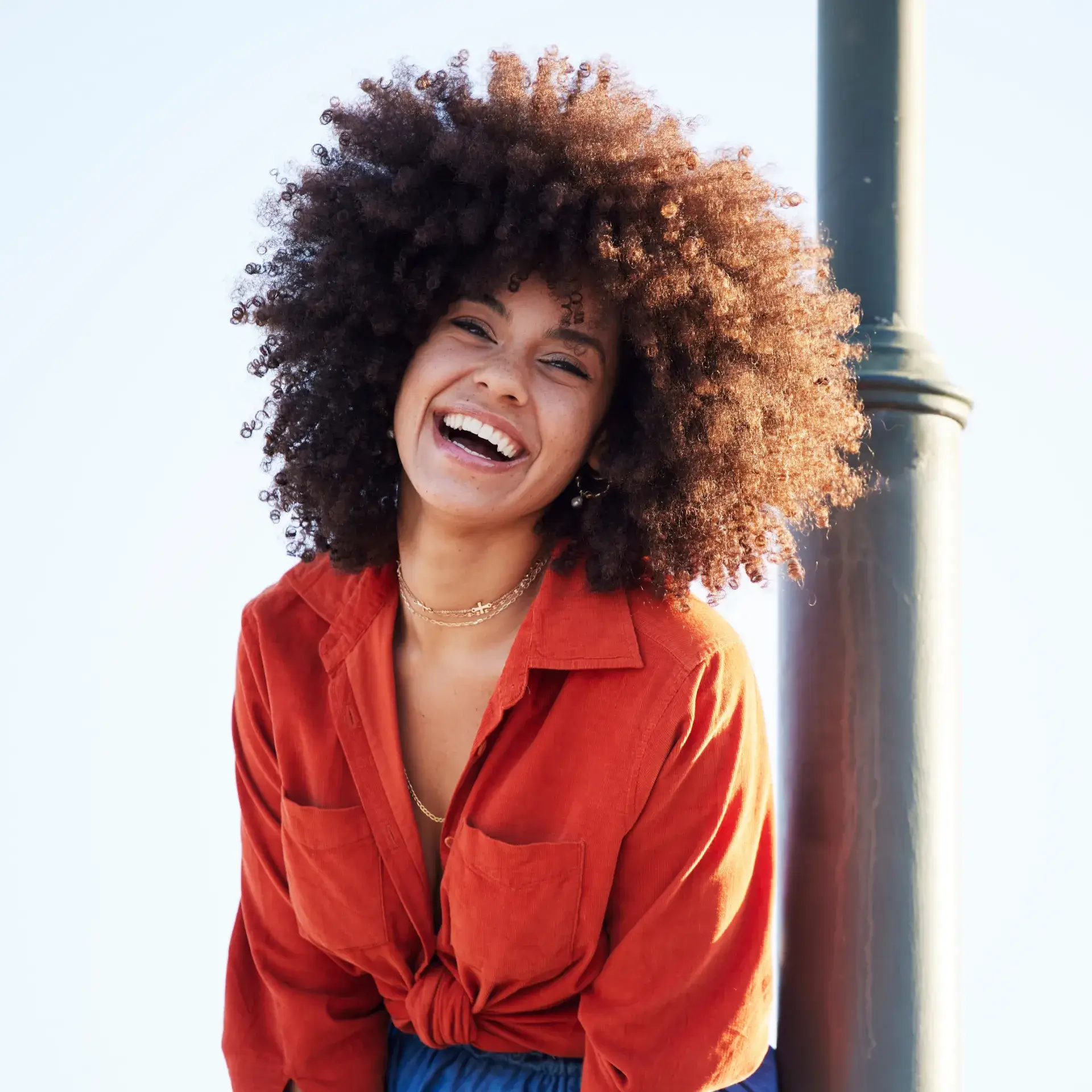 A woman with an afro standing next to a pole.