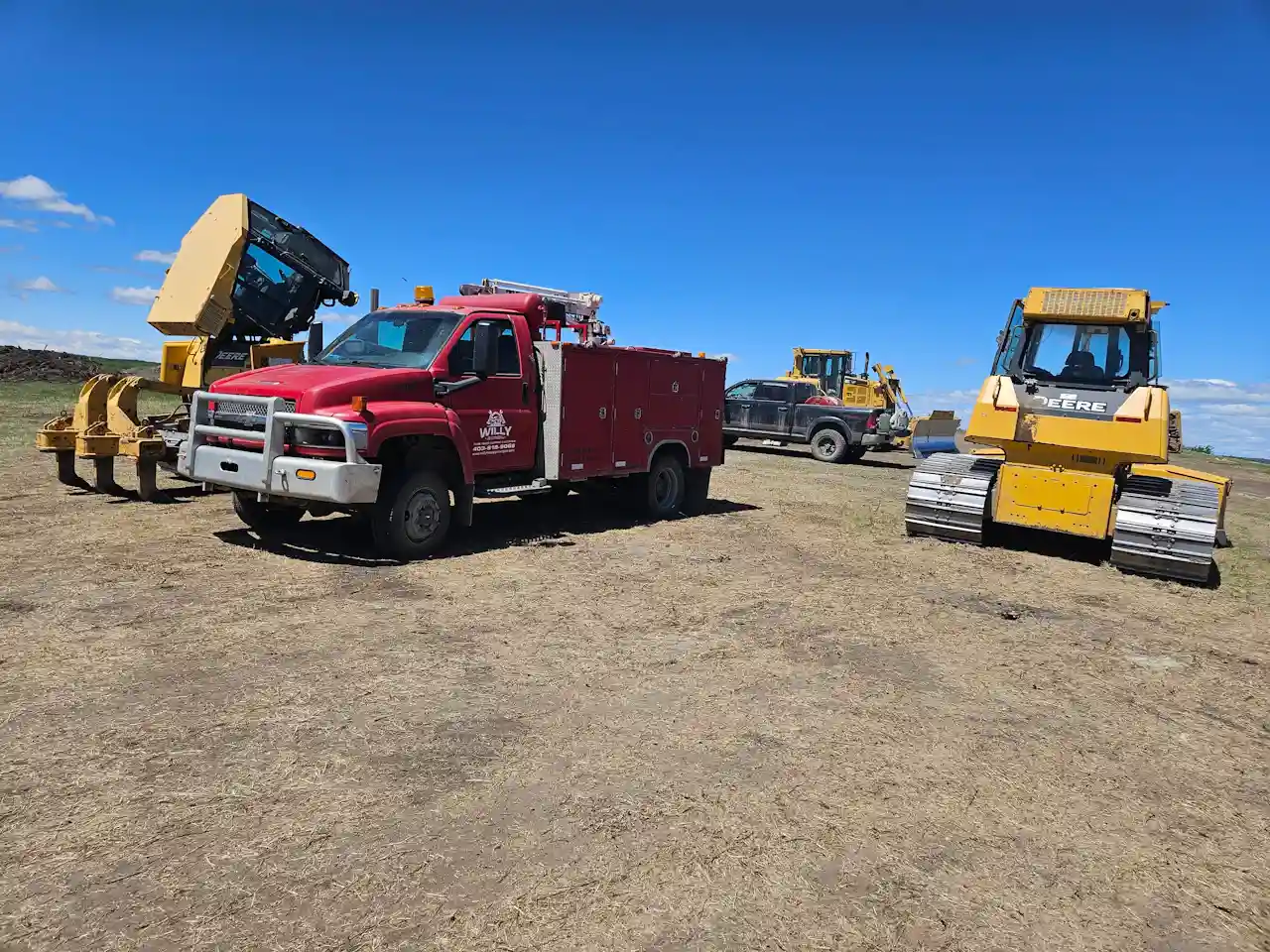 Mobile truck services with a red repair truck beside a TEREX dozer and other heavy equipment at a rural jobsite.
