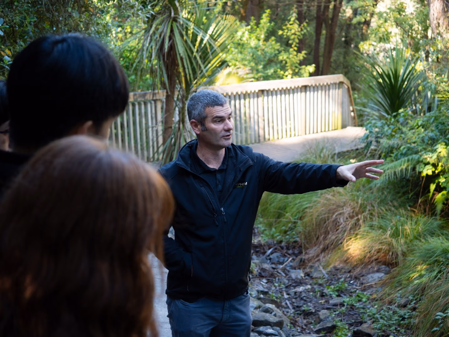 An environmental & three waters engineer from Morphum takes a group of university students on a tour of a naturalised stream project for a stormwater outfall in Auckland, New Zealand