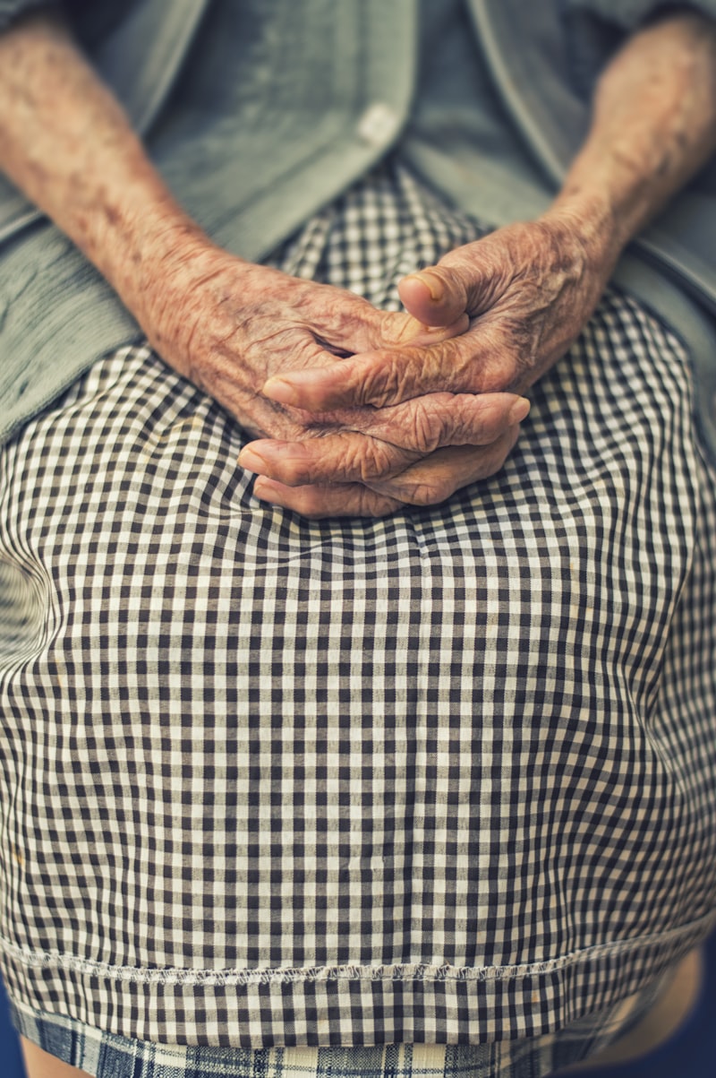 Elderly person's clasped hands showing vulnerability