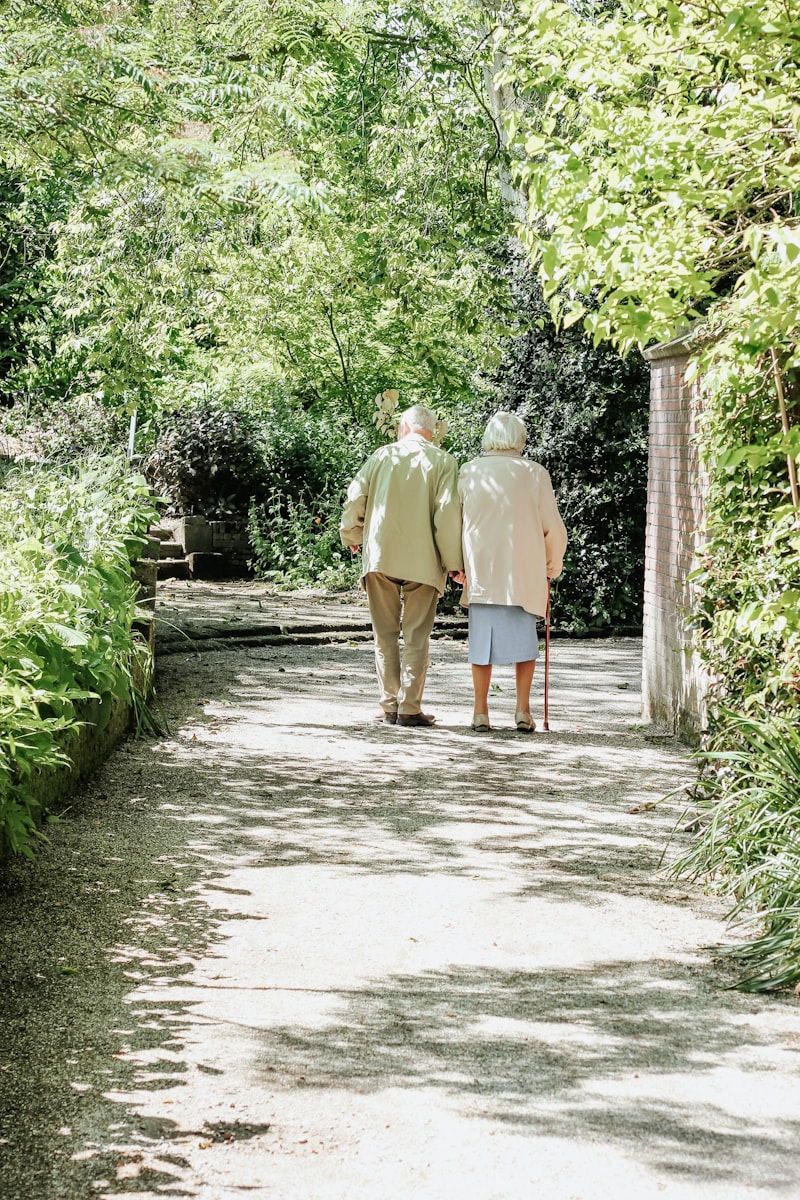 Elderly couple walking together on garden path in warm light