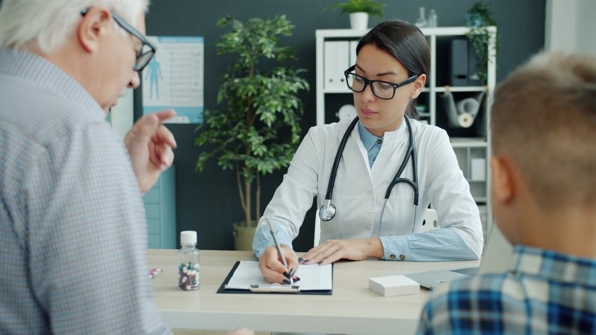 Doctor consulting with elderly patient and family member providing support in a hospital setting