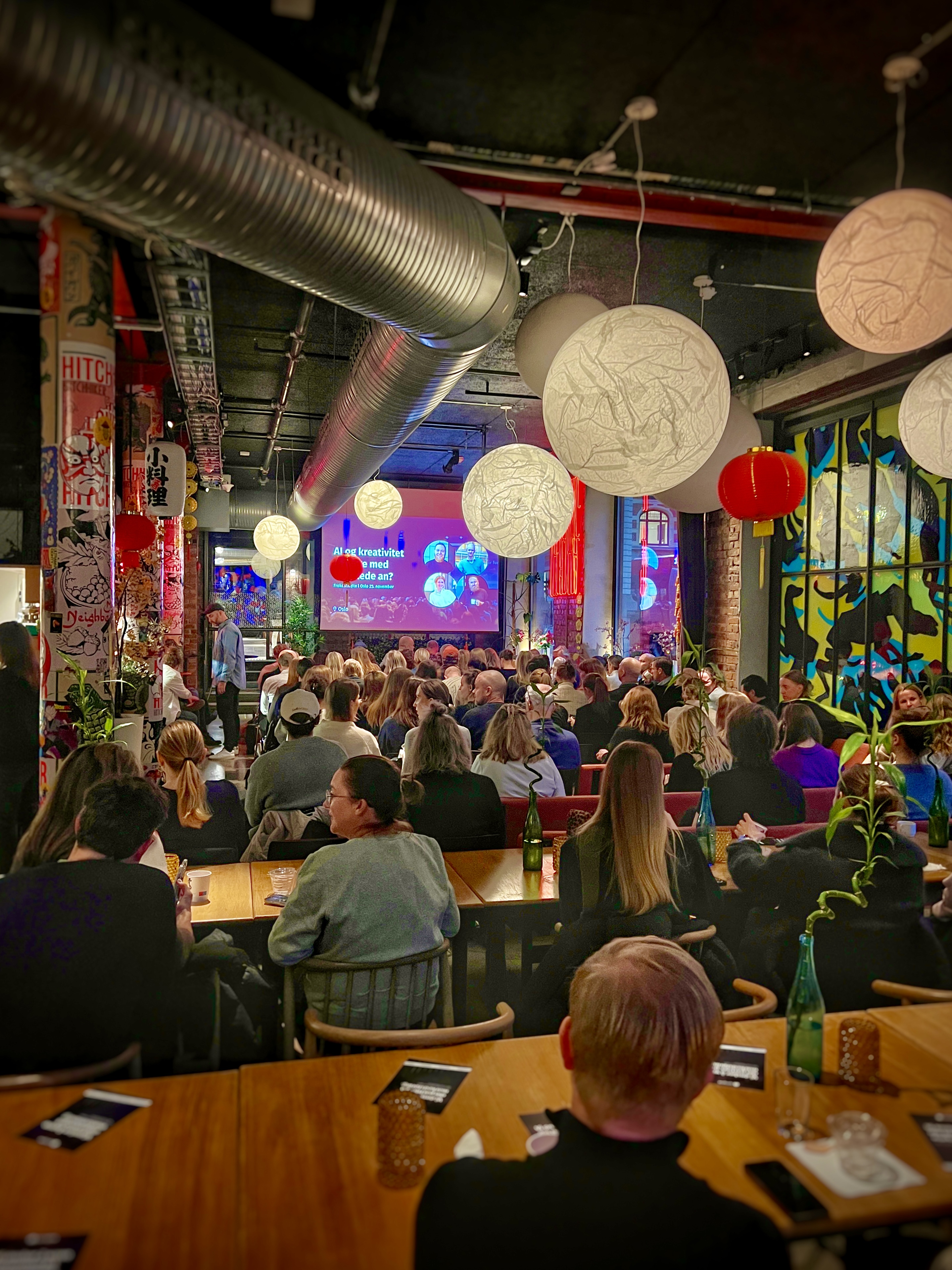 Personer som sitter i Restaurant Hitchhiker og ser på en presentasjon under et frokostmøte.
