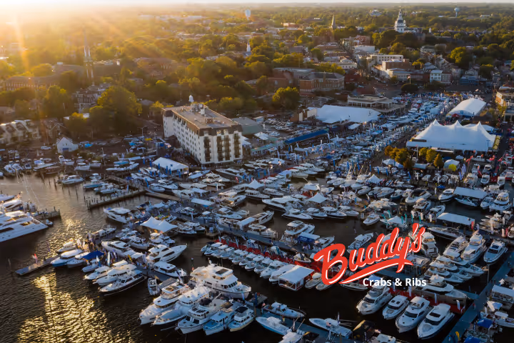 Guests enjoying seafood and waterfront views at Buddy’s Crabs & Ribs in Downtown Annapolis during Memorial Day Weekend, with patriotic decorations and Naval Academy families celebrating nearby.
