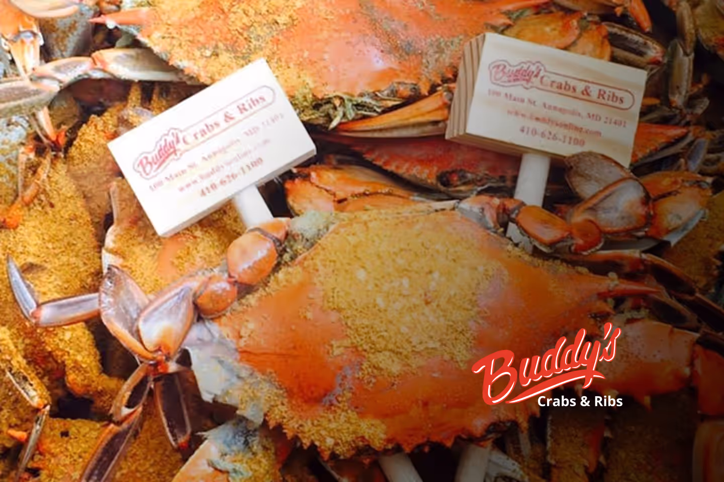 Guests enjoying seafood and waterfront views at Buddy’s Crabs & Ribs in Downtown Annapolis during Memorial Day Weekend, with patriotic decorations and Naval Academy families celebrating nearby.