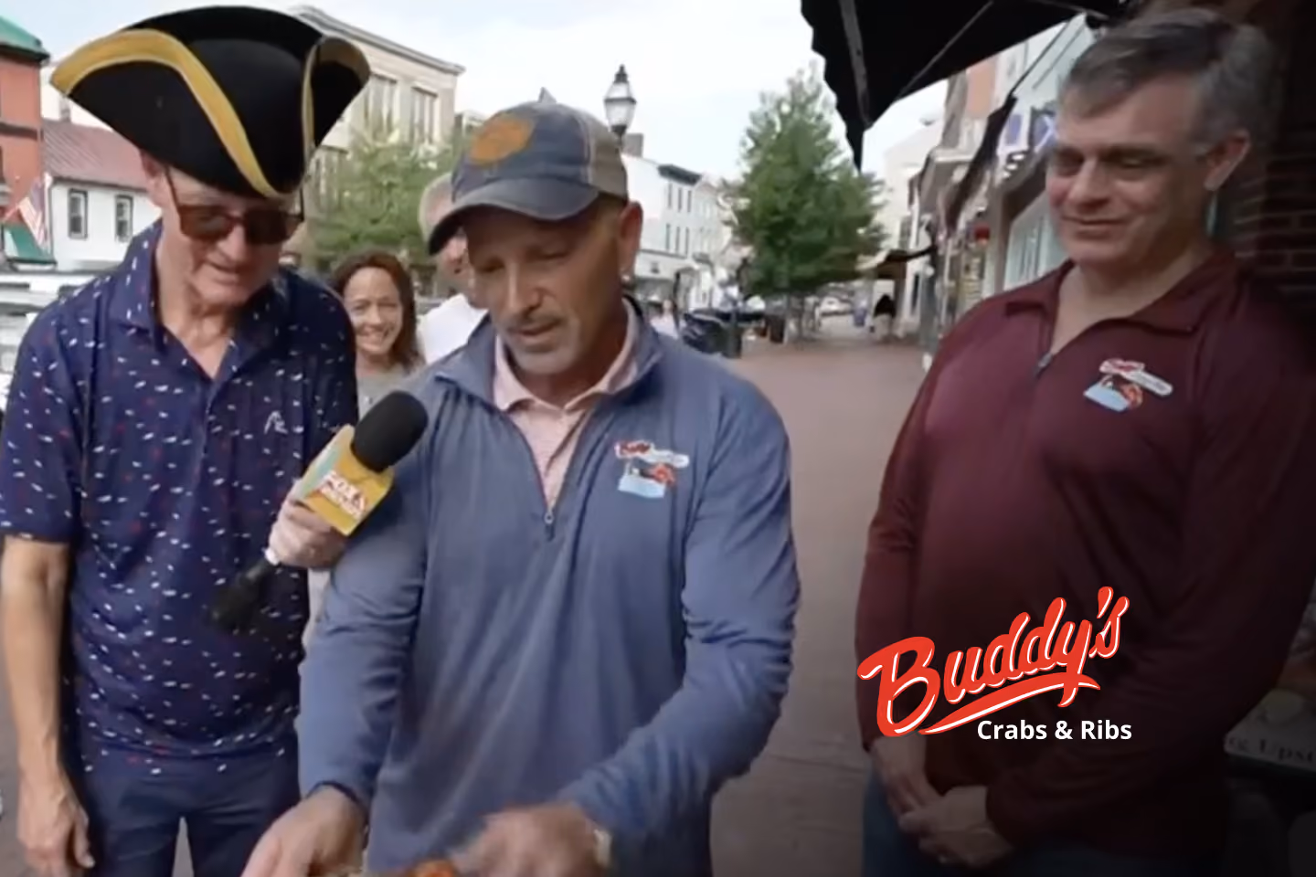 Guests enjoying seafood and waterfront views at Buddy’s Crabs & Ribs in Downtown Annapolis during Memorial Day Weekend, with patriotic decorations and Naval Academy families celebrating nearby.