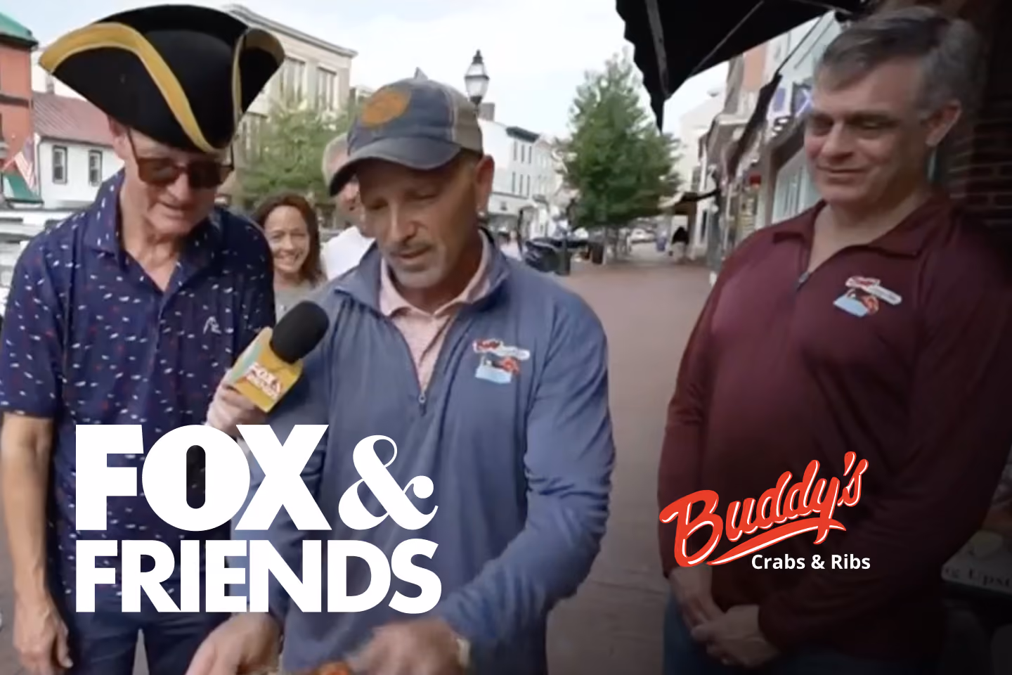 Guests enjoying seafood and waterfront views at Buddy’s Crabs & Ribs in Downtown Annapolis during Memorial Day Weekend, with patriotic decorations and Naval Academy families celebrating nearby.