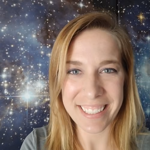 Smiling woman with straight blonde hair and blue eyes standing in front of a starry galaxy backdrop.