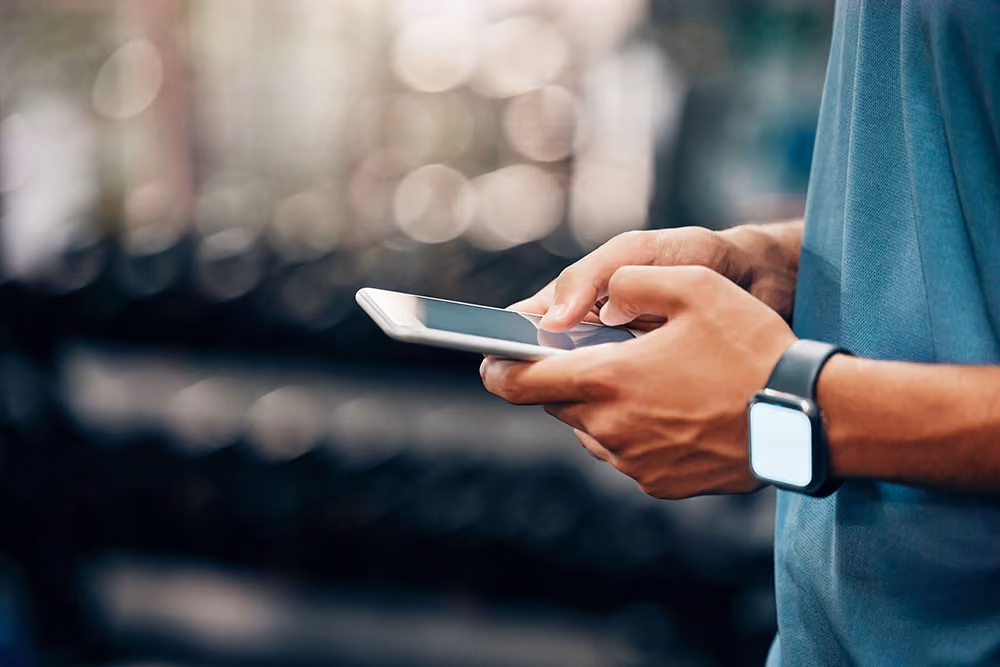 Person wearing a smartwatch and using a smartphone with blurred background.