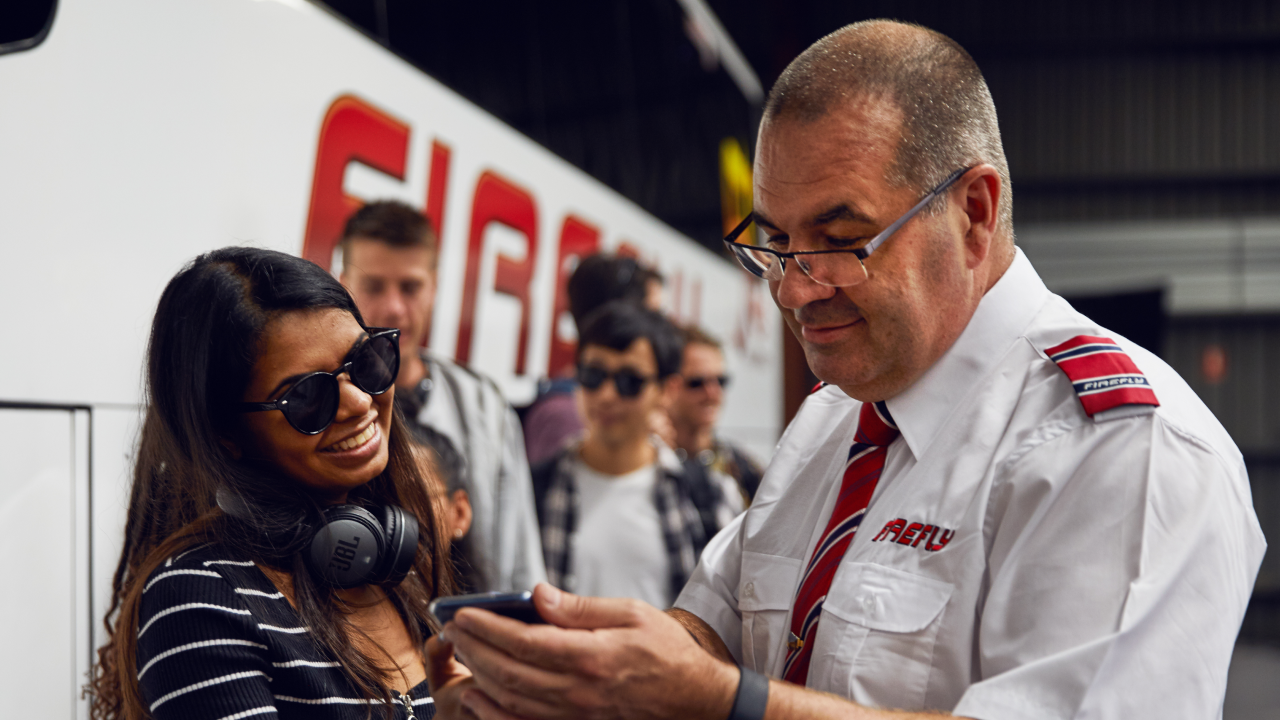 "Passengers boarding a Firefly Express coach with luggage at a city terminal"