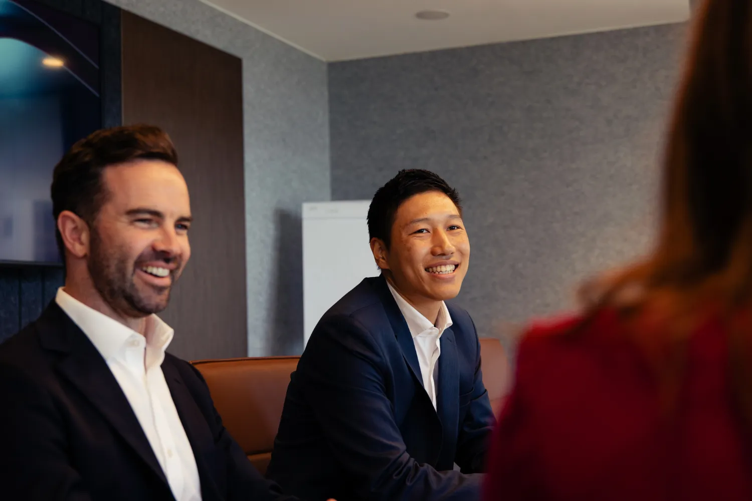 Two Ord Minnett advisers in a meeting, smiling and engaged with a client.