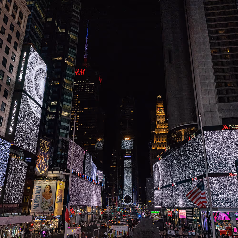 "Pixel Dust" by Leo Villareal on the screens of Times Square at midnight, showing radiating circles of light across a black background