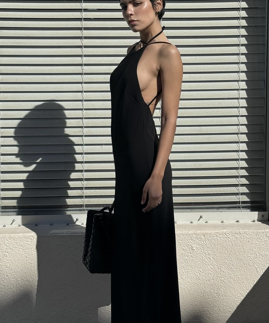 Model in a sleek black gown standing against a city storefront, styled for an influencer shoot
