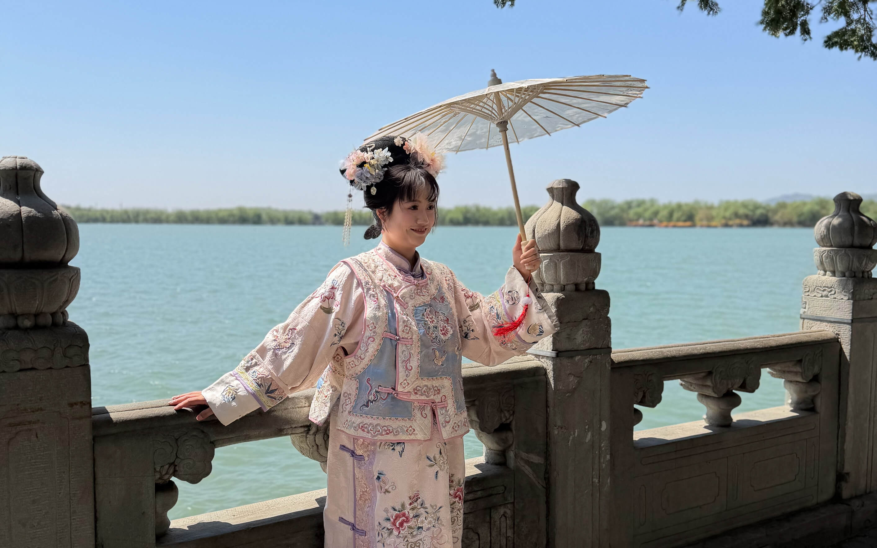 Peking (Beijing), China – Frau in traditioneller chinesischer Kleidung mit Sonnenschirm an einem See während einer China-Reise.