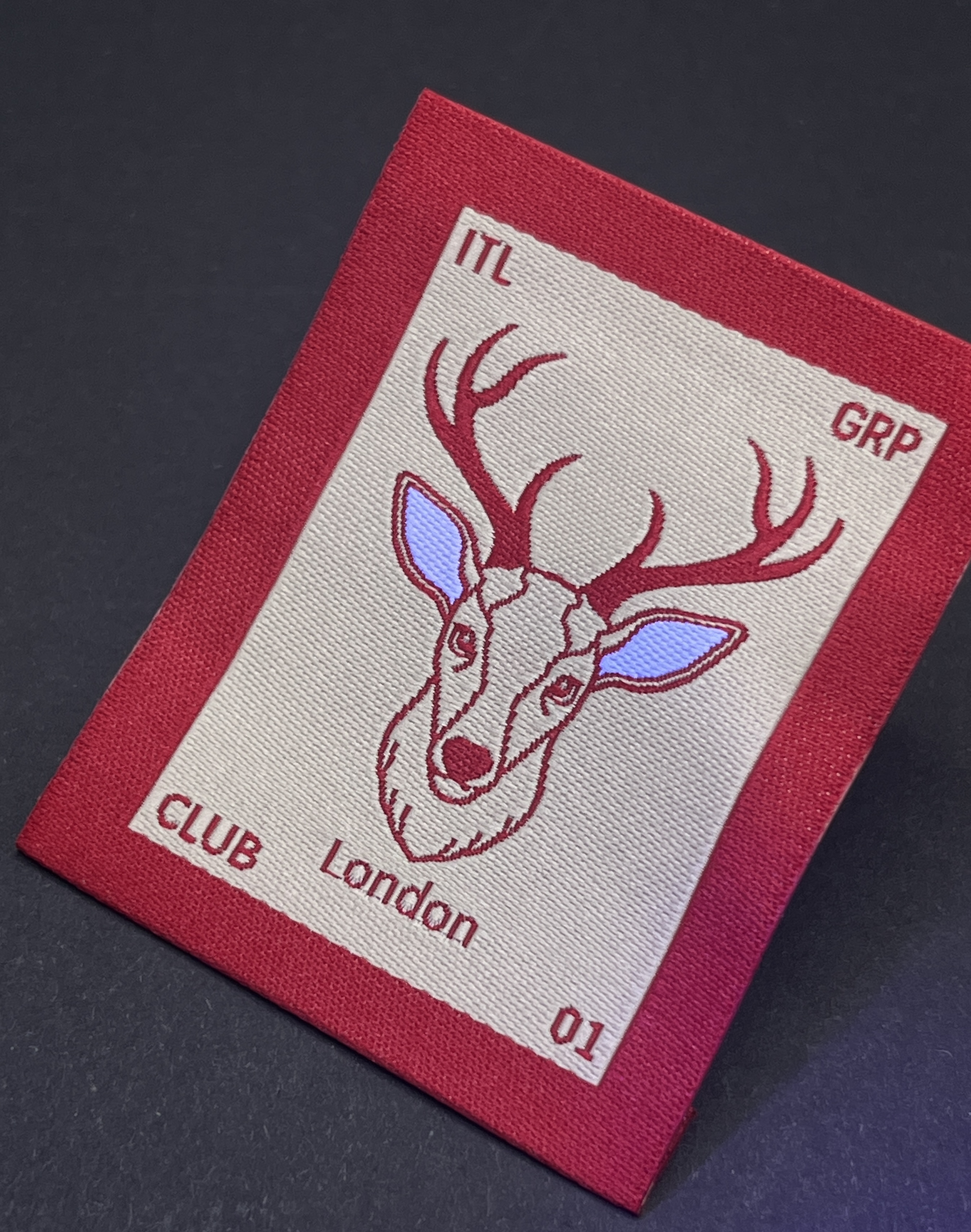 ITL woven deer label under UV light, with the ears woven in UV-reactive yarn glowing blue