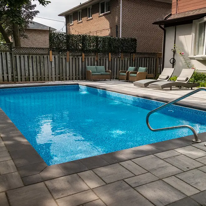 Rectangular inground pool with interlocking paver deck and patio furniture