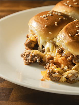 Cheesy Sloppy Joe sliders featuring melted cheddar and mozzarella cheese and seasoned ground beef on Hawaiian sweet rolls, served on a white plate.